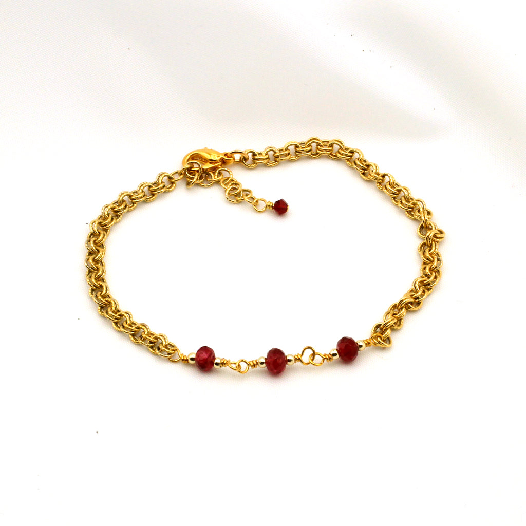 Gold chain bracelet with ruby red crystal bi-cones and adjustable fit.