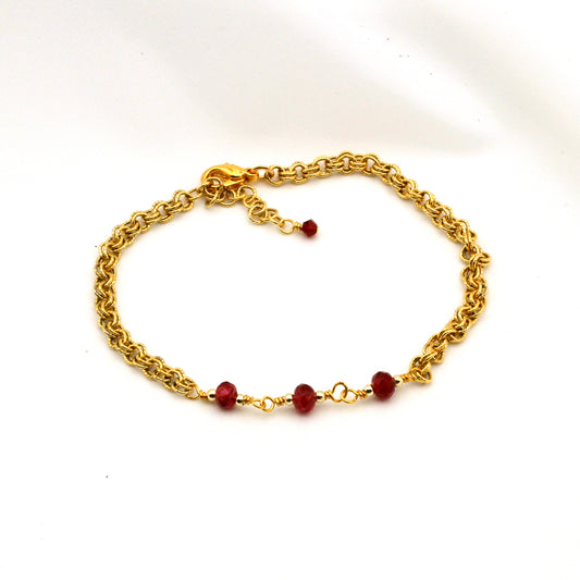 Gold chain bracelet with ruby red crystal bi-cones and adjustable fit.