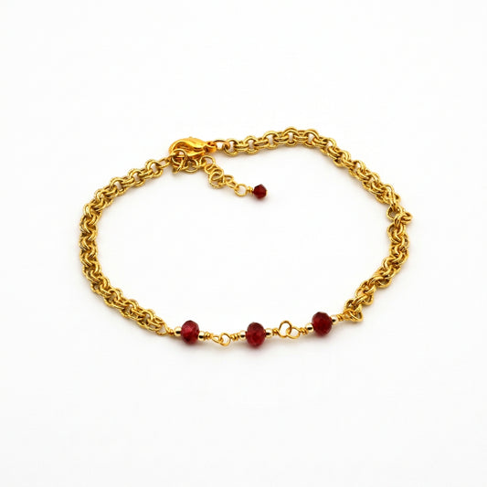 Gold chain bracelet with ruby red crystal bi-cones and adjustable fit.