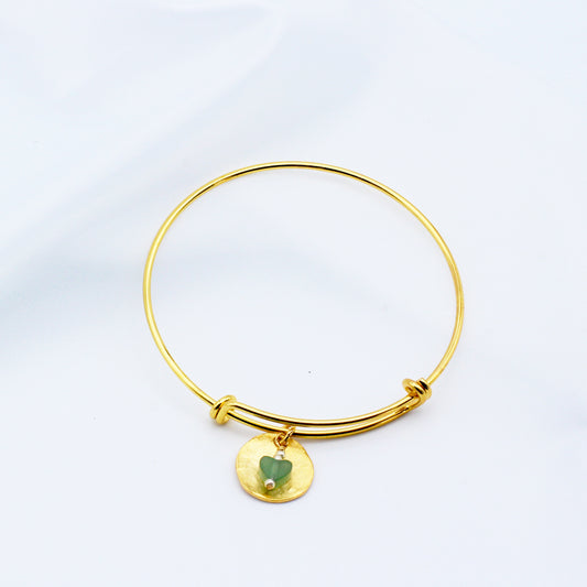 A refined hammered gold disk with a green Aventurine Gemstone dangling from an adjustable bangle.