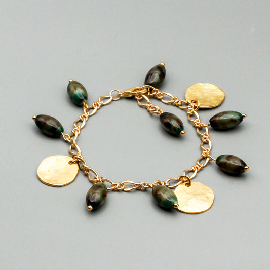 Handcrafted bracelet adorned with vintage oval beads and satin gold disks, this adjustable piece will beautifully accentuate your wrist.