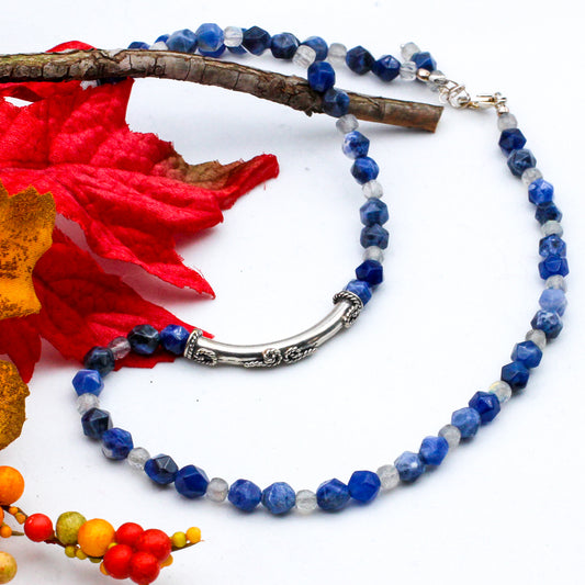 A gorgeous necklace that features stunning sodalite and labradorite gemstones, the focal point of the necklace is a modern sterling silver tube bead with intricate scroll designs.