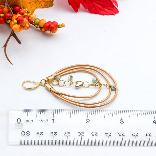 Hoop earrings with gold leather, mint green crystals, and matte gold chain.