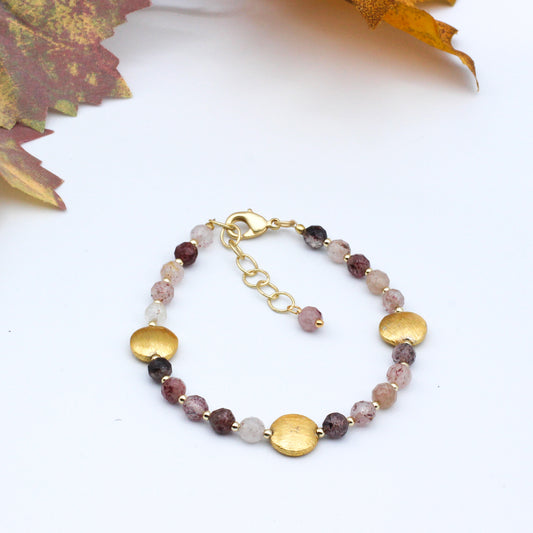 Bracelet features Strawberry Quartz Gemstones and delicate Gold accent disks, with adjustable chain closure.