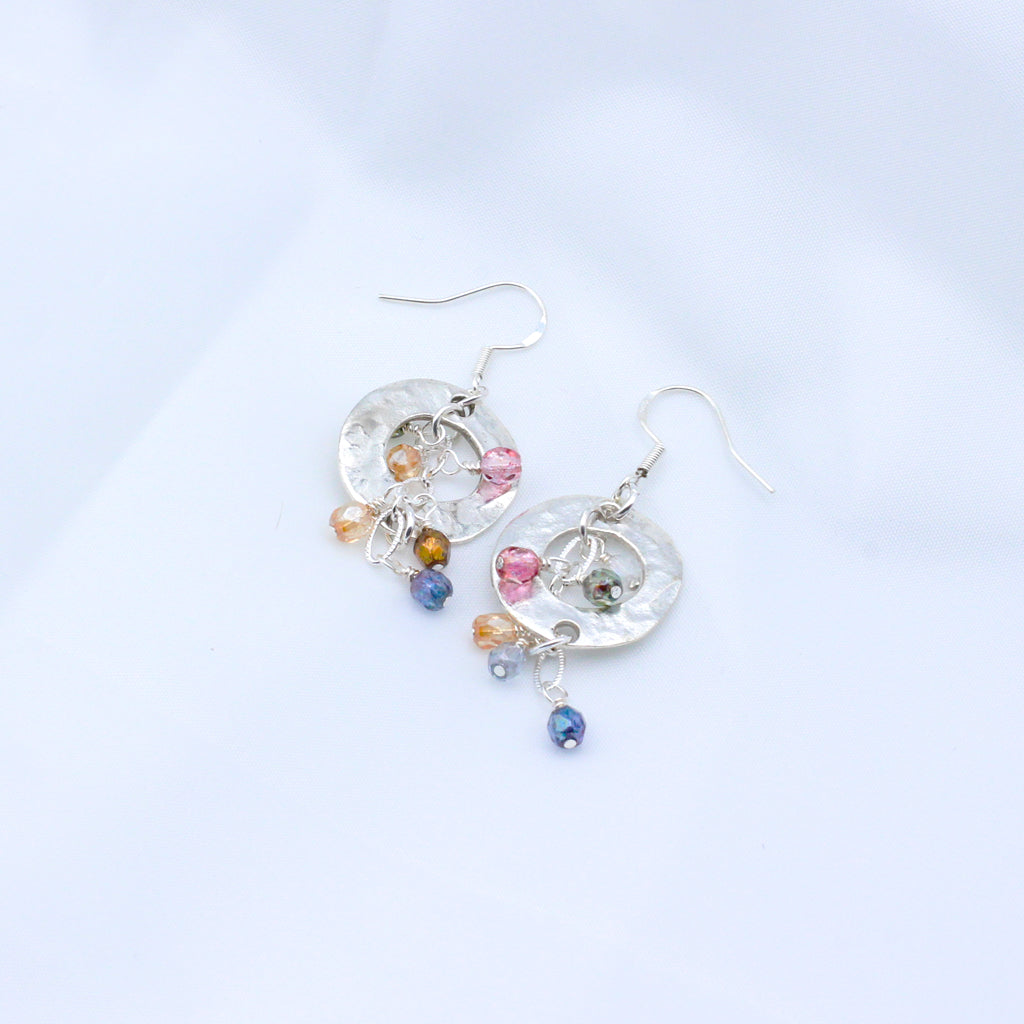 Soft pastel tones with these Bubbly Rose' earrings. Adorned with delicate crystals encircling a striking hammered disc centerpiece.