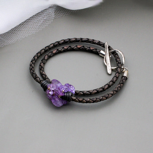 Amethyst gemstone beads twist around edgy braided dark gray leather. It is finished with a silver toggle clasp.
