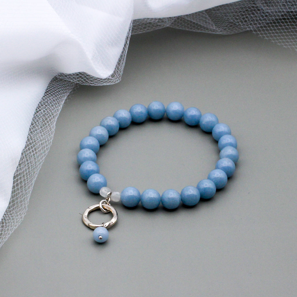 Angelite Gemstone beads and iridescent rainbow Moonstone beads, accented by high-quality sterling silver metals with an strong elastic band for a comfortable and easy fit.