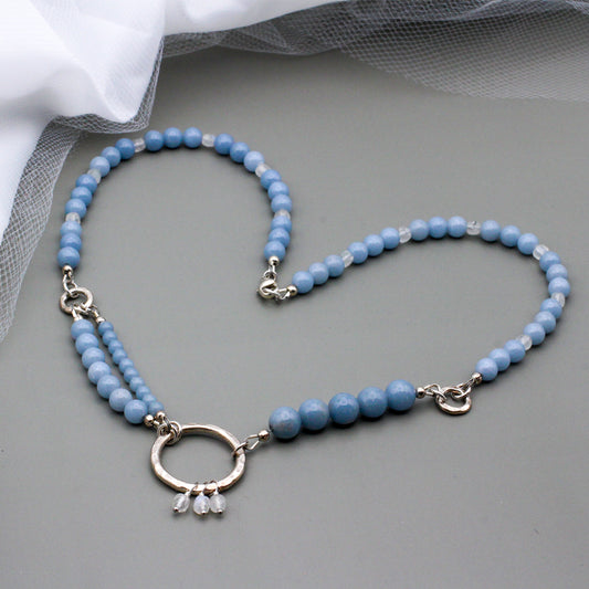 Angelite Gemstone beads, rainbow Moonstone beads, and Sterling Silver. Textured Sterling Silver ring as the focal point, completed with a lobster claw clasp.