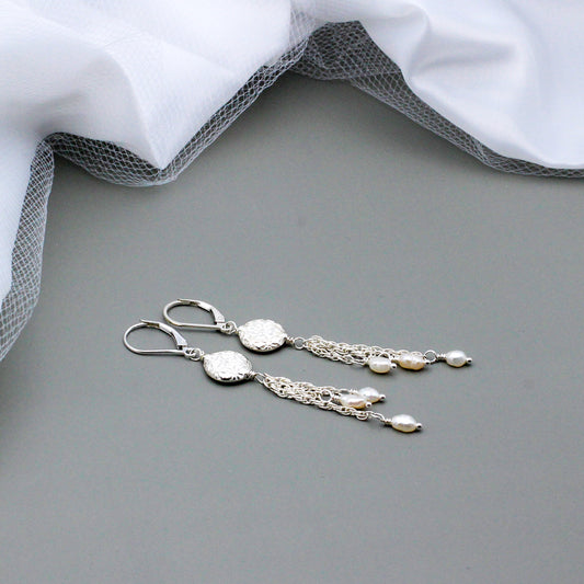 Three lustrous white freshwater pearls gracefully sway from varying lengths of chain, creating an enchanting effect.
