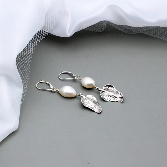 Adorned with a lustrous freshwater pearls each earring is gracefully accented by a delicate sterling silver leaf charm.
