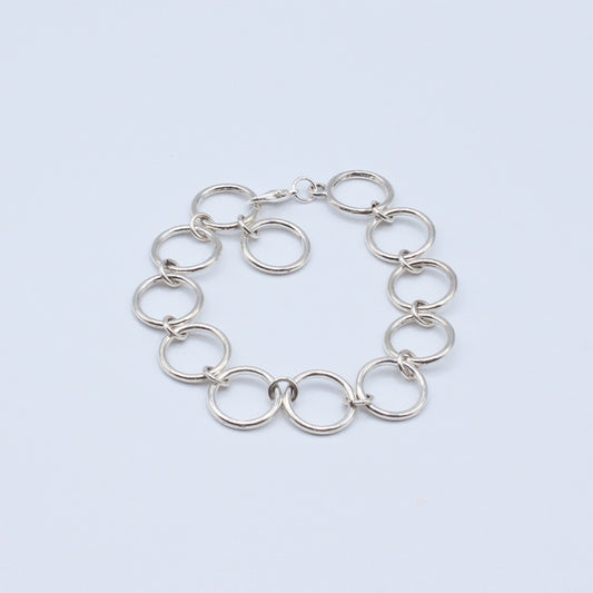Connected rings bracelet featuring a refined lobster clasp mechanism that allows seamless length adjustment 