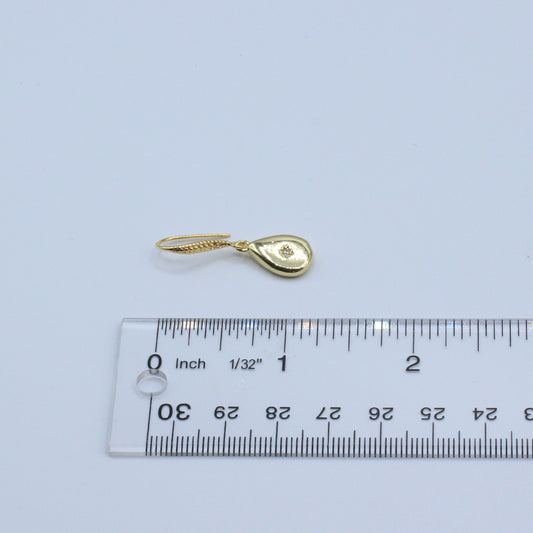 Gold teardrop-shaped pendant with a heart design on a light gray background, measured against a ruler.