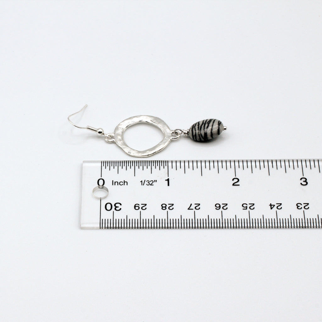Silver earrings with black and white striped beads on a light gray background