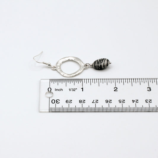 Silver earrings with black and white striped beads on a light gray background