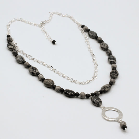 Necklace with black and gray beads and a silver pendant on a white background