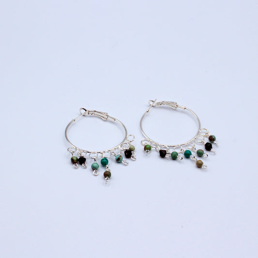 These hoop earrings feature a 1 1/2"" diameter and are crafted with African Turquoise stones. They incorporate silver electroplated metals.