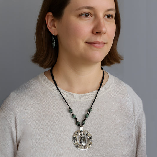 This necklace offers adjustable length from 20" to 32" and features African Turquoise beads complemented by a pewter focal piece and spacers, all strung on soft suede for a sophisticated look.