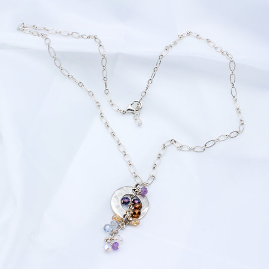 Pastel colors with a blend of delicate crystals, shimmering silver electroplated metals, and a hammered disk focal. 