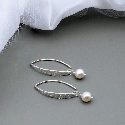 Adorned with freshwater cultured pearls, these earrings feature a sculptural Sterling Silver oval Hoop.